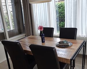 Dining room of vacation home De Anemoon in De Koog, Texel, with wooden table and stylish chairs.
