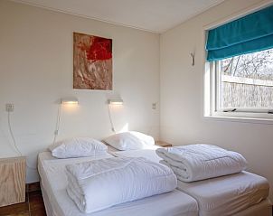 Schlafzimmer des Ferienhauses De Zonneweelde in De Koog, Texel, mit Doppelbett und Kunst an der Wand.