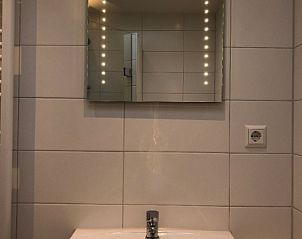 Illuminated sink in 't Buitenhuisje, vacation home De Koog Texel, with mirror and modern bathroom accessories.