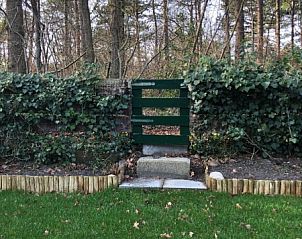 Green garden and natural surroundings at 't Buitenhuisje, vacation home De Koog Texel, with entrance gate.