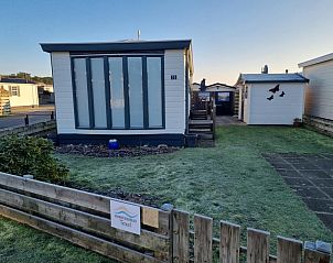 Chalet Bregkoog 33 in Chaletpark Bregkoog, De Koog, Texel, offers a serene outdoor space with a manicured lawn and wooden fence.