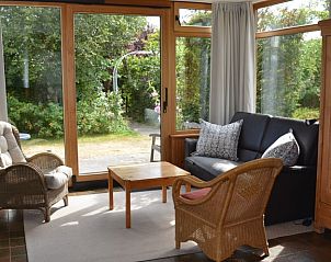 Gezellige woonkamer van Vredelust 283 bungalow in De Koog, Texel, met uitzicht op tuin.
