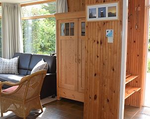 Woonkamer met houten kast in Vredelust 283 bungalow, De Koog, Texel, omgeven door natuur.