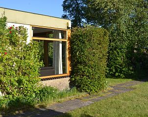 Zijaanzicht van Vredelust 283 bungalow, De Koog, Texel, met groene heg en pad.