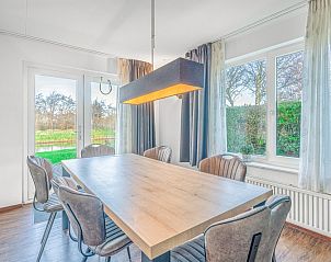 Dining area in Holiday home Honeysuckle 51, De Koog, Texel, with large windows and views of the green surroundings.
