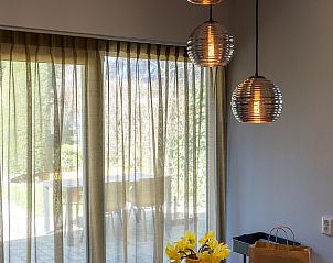 Dining table with flowers in Zilte Bries vacation home, De Koog, Texel, overlooking terrace.