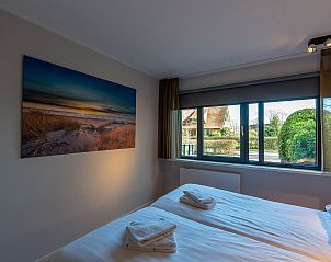 Bedroom with view in Zilte Bries vacation home, De Koog, Texel, with art on the wall.