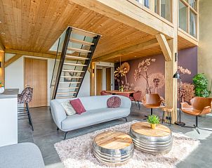 Open living space in Villa 187 with Hot tub, De Koog, Texel with wooden beams and artistic wall decoration, ideal for a vacation on the Wadden Islands.