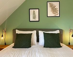 Stylish decoration in bedroom of De Boomleeuwerik vacation home, De Koog, Texel with art on the wall.