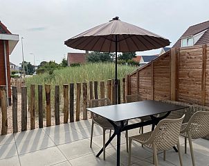 Sunny terrace with parasol in De Boomleeuwerik vacation home, De Koog, Texel, ideal for outdoor dining.