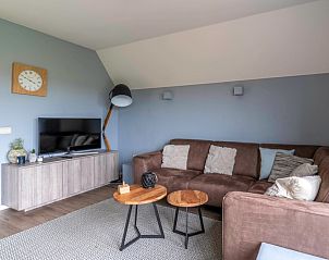 Stilvolle Sitzecke im Ferienhaus Nieuwlanderweg 77, De Koog, Texel, mit bequemem Sofa und Flachbildfernseher, ideal zum Entspannen.