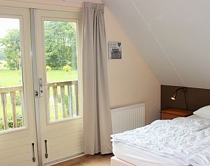 Schlafzimmer mit Balkon in 6p.reetgedecktem Ferienhaus Eldorado Texel, De Koog, mit Blick auf die Natur.