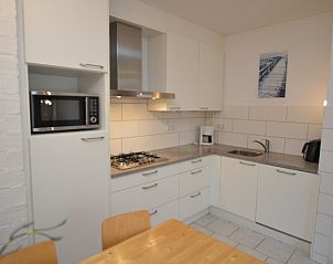 Fully equipped kitchen in Apartment Kerckeland 24, De Koog, Texel with sleek finish and dining table.