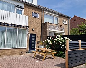 Exterior of Holiday home Duinzee Texel in De Koog with sunny terrace and colorful flowers.