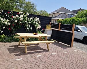 Cozy terrace at Holiday home Duinzee Texel in De Koog with picnic table and flowering roses.