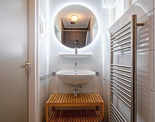 Stilvolles Badezimmer in Het Paviljoen, Ferienhaus in De Koog, Texel mit beleuchtetem Spiegel und Waschbecken.