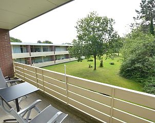 Balcony of Apartment Kerckeland 126, De Koog, Texel, overlooking green surroundings and seating area.