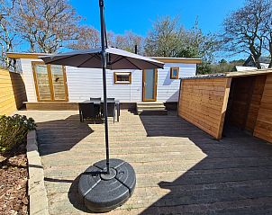 Veranda of Chalet Out and Home in De Koog, Texel, with wooden fence and parasol.