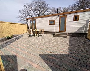 Spacious terrace of Chalet Out and Home in De Koog, Texel, with garden furniture and fence.