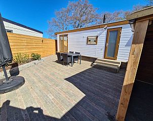 Sunny terrace of Chalet Out and Home in De Koog, Texel, with wooden fence and garden furniture.