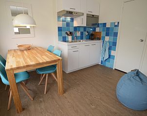 Dining room and kitchen in Grand Hotel Opduin - Holiday home B, De Koog, Texel with wooden table and colorful chairs.