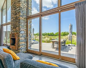 Groot raam met uitzicht op terras in Vakantiehuisje in De Koog, Texel.