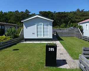 Front view of Chalet Bregkoog 205, a vacation home in De Koog Texel with green surroundings.