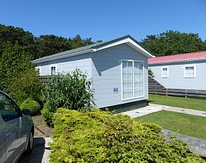 Side view of Chalet Bregkoog 205, a vacation home in De Koog Texel surrounded by greenery.