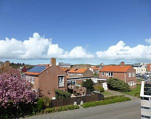 Blick von Apartments Anna - Apartment 15 in De Koog, Texel, mit charmanten Husern und blauem Himmel.