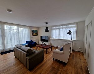 Gezellige zitkamer in Bungalow Epelaan 13, De Koog, Texel, met zithoek en grote ramen voor veel daglicht.