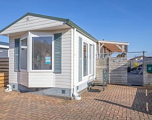 Vorderansicht von Chalet Bregkoog 27 in De Koog, Texel, mit sonniger Terrasse und modernem Aussehen.