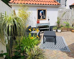 Cozy patio at Texel D vacation home in De Koog, Texel with colorful flowers and comfortable seating areas.