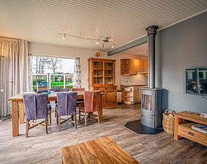 Open kitchen and dining area in Orchismient 2, vacation home De Koog, Texel with wood stove and large windows.