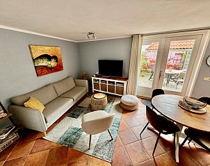 Gezellige woonkamer in vakantiehuis Texel A, De Koog, met comfortabele zithoek en uitzicht op de tuin.