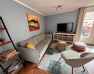 Comfortabele zithoek in Texel A, De Koog, met flatscreen-tv en toegang tot het terras.