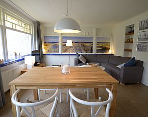 Spacious dining room in Grand Hotel Opduin - Holiday home C, De Koog, Texel, with wooden table and cozy living room.