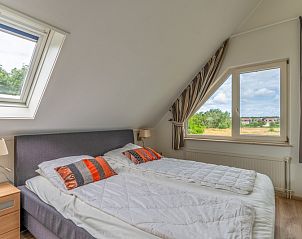 Bedroom with double bed in Holiday home Kamperfoelie 69 with sauna, De Koog, Texel, overlooking the surroundings.