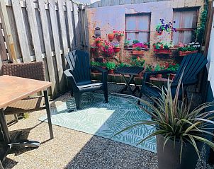 Private terrace of Texel C vacation home in De Koog, Texel, with comfortable chairs and colorful flowers.