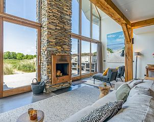 Cozy living room in Villa 193, De Koog, Texel, with fireplace and views of the natural surroundings.