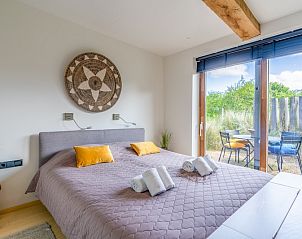 Bedroom in Villa 193, De Koog, Texel, with comfortable bed and access to private terrace, surrounded by nature.