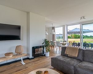 Modern living room of Orchismient 17 vacation home in De Koog Texel with large windows and landscape views.