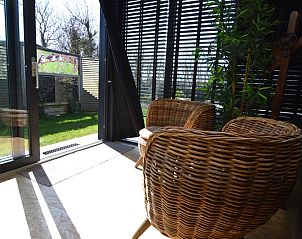 Ferienhaus Hoog Koog 8 in De Koog Texel, Sitzecke mit Gartenblick und dekorativen Elementen.