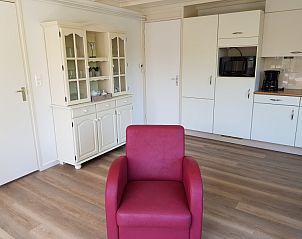 Cozy interior of Bungalow 5100 on Texel with red chair.