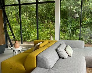 Bright living room in De Koerie vacation home De Koog Texel overlooking lush greenery, perfect for rest.