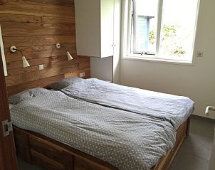 Comfortable bedroom in De Koerie vacation home De Koog Texel with wooden accents and serene look.