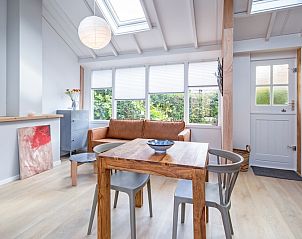 Gemtlicher Innenbereich des Ferienhauses Pippa, De Koog, Texel, mit bequemem Sofa und Essecke.