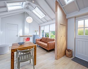 Stilvolles Wohnzimmer des Ferienhauses Pippa auf Texel mit Holzinterieur und groen Fenstern.