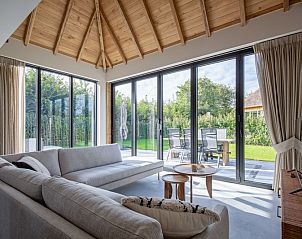 Bright living room of Villa Jolie in De Koog, Texel, with large windows and views of the green surroundings.