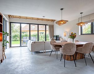 Modern dining room in Villa Jolie, De Koog, Texel, overlooking the garden and comfortable seating.