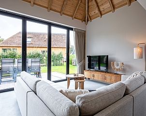 Lounge area in Villa Jolie, De Koog, Texel, with large windows and views of the garden and surroundings.